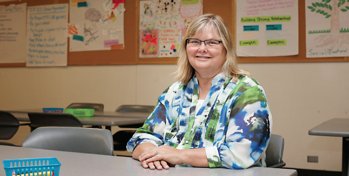 Beth Marshall, WCC’s Early Childhood Program coordinator and faculty, sits in front of childhood development posters created by her students. (Photo by Kelly Gamel)