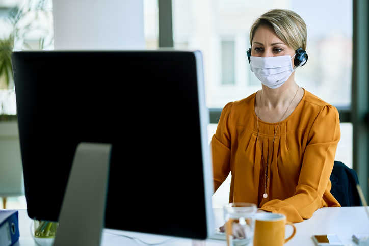 Online learner in front of laptop wearing covid mask