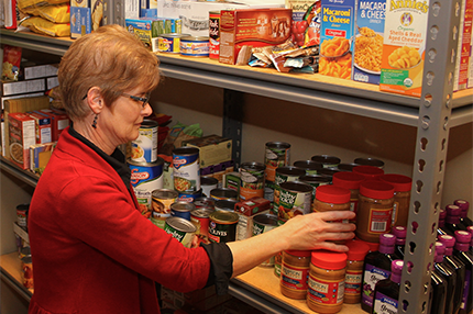 Carol TInkle, an administrative assistant in the Washtenaw Community College Counseling and Career Planning department, stocks the shelves of the college’s student food pantry. Tinkle oversees operations of the food pantry. | Photo by Lynn Monson